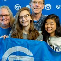 A family photo of alumni holding the GV flag
